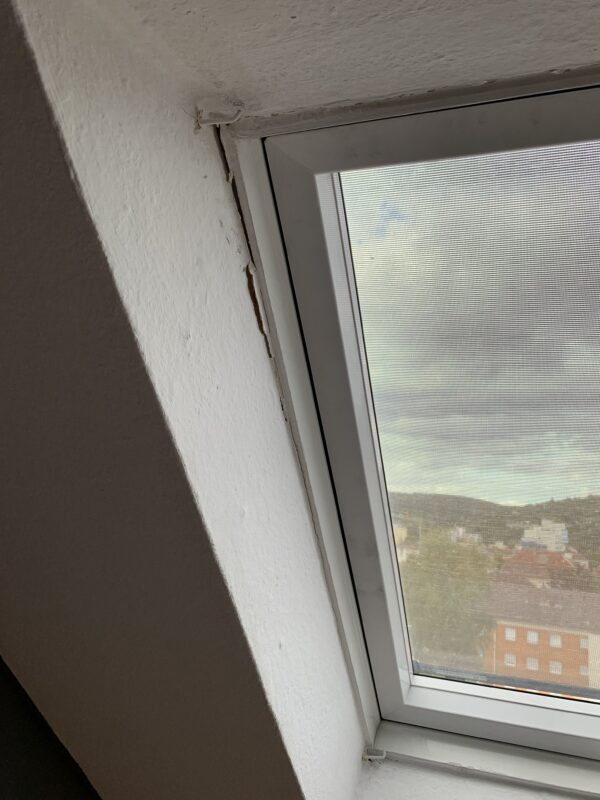 Innenansicht eines defekten eingebauten Kunststoff-Dachfensters vor der Reparatur, bei dem die Verkleidung nicht mehr sauber abschließt.