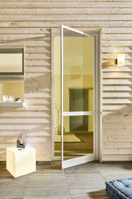 Geöffnete Terrassentür mit eingesetztem Insektenschutzrahmen in einem modernen Holzhaus.